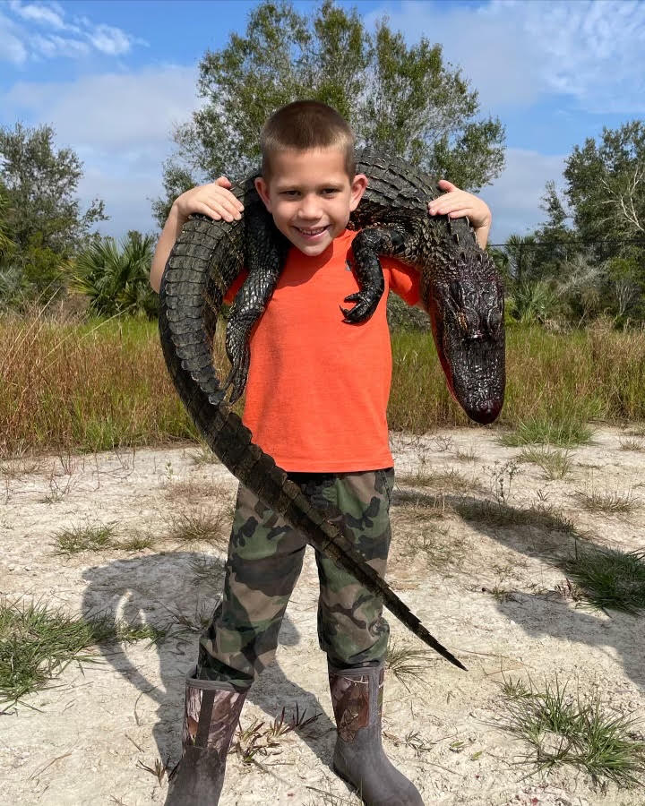 small child showing off the gator he hunted in florida