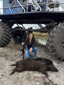 female posing with wild hog she hunted on our private property in a buggy